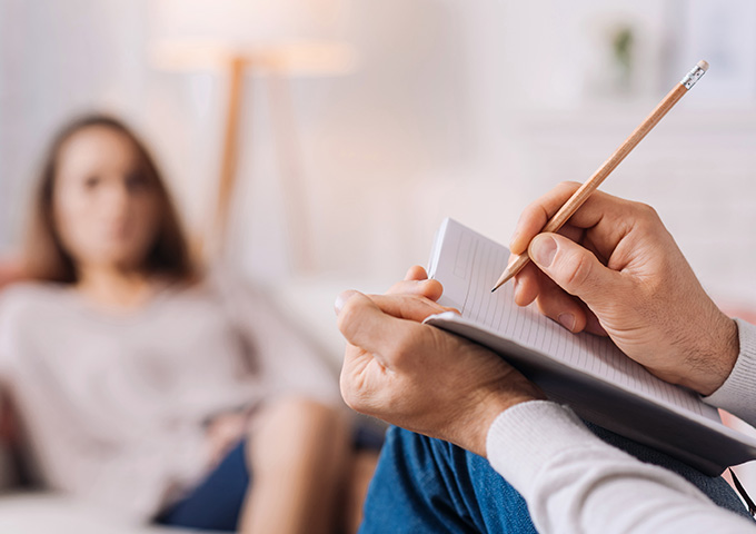 Therapist taking notes during a solution focused hypnotherapy session.