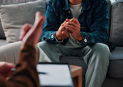A person seated on a sofa engaged in a therapeutic conversation, showcasing a comfortable therapy environment.