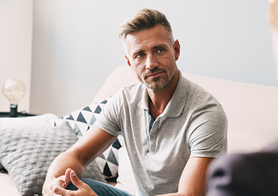 A man engaging in a therapy session, sitting on a sofa in a comfortable room.