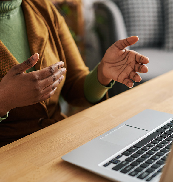 Hands gesturing during an online hypnotherapy session, viewed from above a laptop.