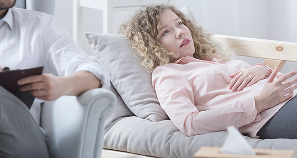 Client in solution focused hypnotherapy session with a therapist in a comfortable therapy room.