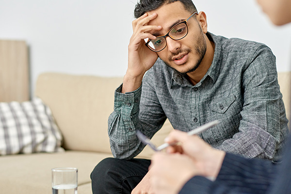 Client experiencing stress during a therapy session with a hypnotherapist.