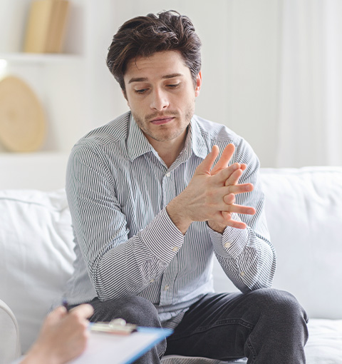A man sitting on a couch appears contemplative during a therapy session.