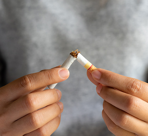 Breaking a cigarette in half to symbolize quitting smoking.