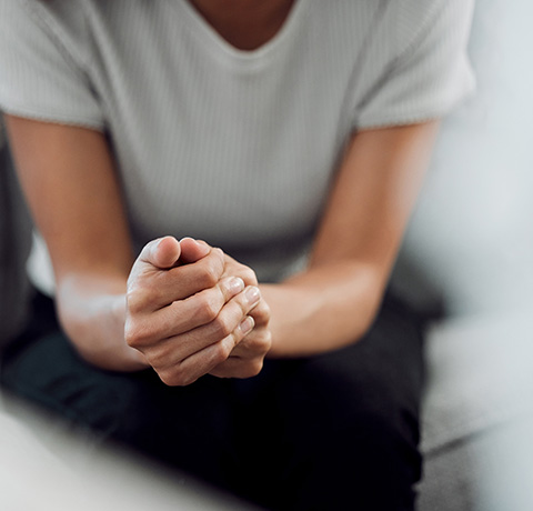 Person sitting with clasped hands, reflecting a moment of contemplation or relaxation.