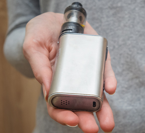 A person holding a silver vaping device, suggesting addiction therapy services.