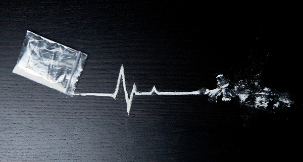 A bag of white powder with a heartbeat line drawn in white powder, symbolizing addiction and its impact.